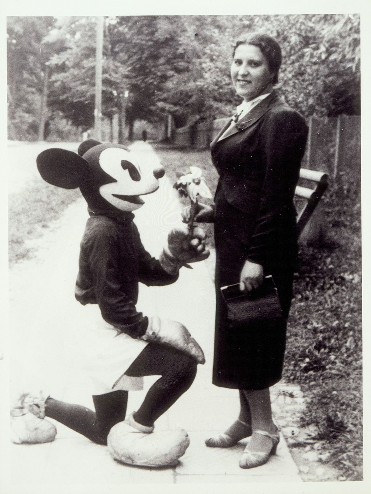 Esther Lapp poses with a person dressed as Mickey Mouse in Eisiskes. Courtesy of United States Holocaust Memorial Museum.